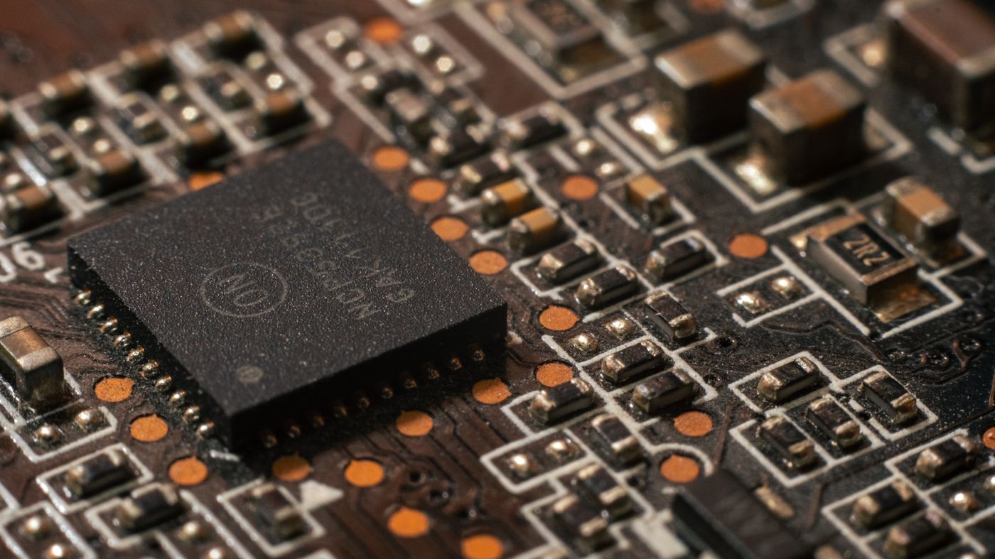 Close-up macro of a populated printed circuit board with a central integrated circuit and copper pads